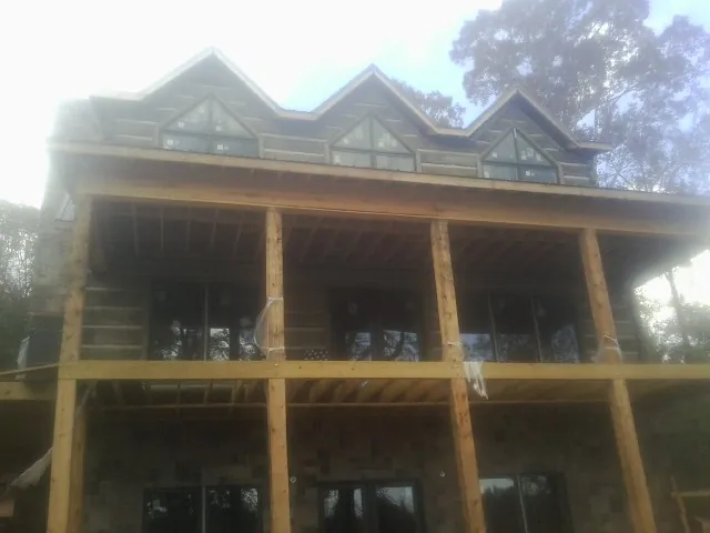 Dormers and porch framing on a large log home under construction — Roof Coating work by our crew in Maury