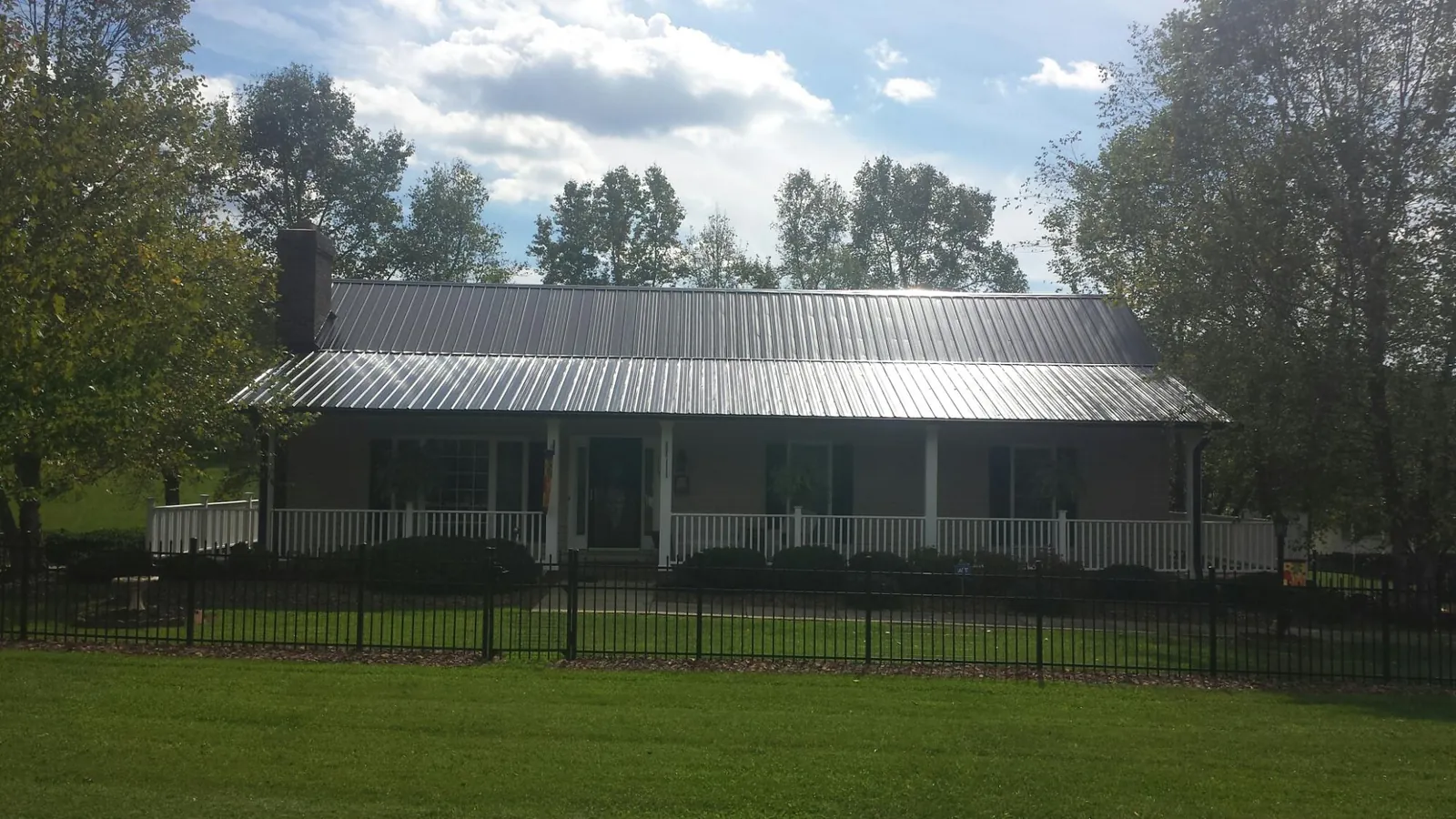 Gray metal roof on a brick ranch with a full width front porch — Gutter Guard Installation work by our crew in Maury