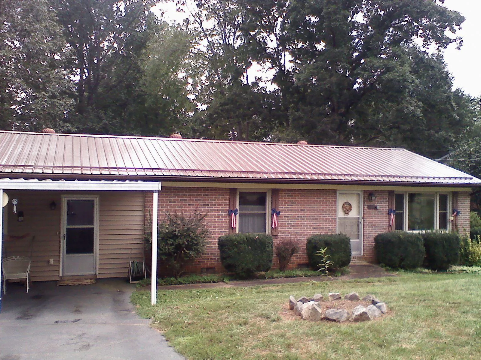 Bronze metal roof and carport on a brick ranch home — Roof Repair work by our crew in Maury